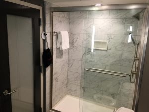 The marble shower looks very enticing with its glass doors.